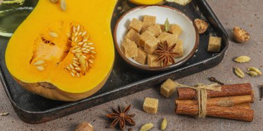 Koyu bir tepside yarım tereyağlı ezme ve içinde pişirme malzemeleri var. Esmer şeker, tarçın çubukları, zencefil, hindistan cevizi. Geleneksel sonbahar turtası ve tatlı tarifleri için baharatlar, sıcak kahverengi arka plan, pankart formatı