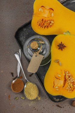 Koyu bir tepside yarım tereyağlı ezme ve içinde pişirme malzemeleri var. Esmer şeker, tarçın çubukları, zencefil, hindistan cevizi. Geleneksel sonbahar turtası ve tatlı tarifleri için gerekli baharatlar, sıcak kahverengi arka plan, üst manzara.
