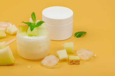 Naneli ve buzlu doğal kavun sulandırıcı krema. Beyaz kozmetik kavanozları ve canlı bir arka planda yaz cilt bakımı için taze meyve, kopyalama alanı