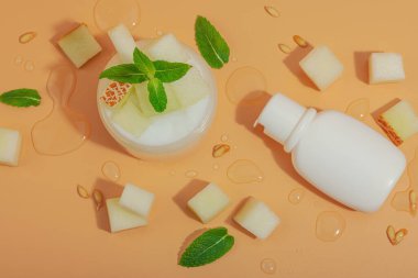 Doğal kavun özü cilt ürünleri. Krema kavanozu, losyon şişesi, nane yaprakları ve tatlı su damlaları yumuşak arka planda, üst tarafta.