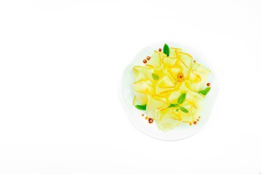 İnce dilimlenmiş karpuz carpaccio aperatifi taze nane ve balzamik sosla beyaz tabağa düşer. Gurme, sağlıklı yemek ve üst manzara için izole edilmiş gıda tasarımı.