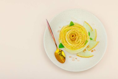 Nane, baharat ve seramik tabakta pembe tuz kristalleriyle süslenmiş çiçek şeklinde zarif bir kavun carpaccio tatlısı. Hafif şeftali arkaplan, üst görünüm