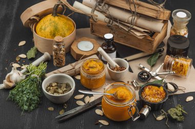 Kabak püresi, humus, bitkiler, kurutulmuş baharatlar, antika makas ve koyu ahşap arka planda antika nesnelerin yer aldığı taşralı natürmort hayat. Eczacı konsepti veya cadı ruhu, yaklaşın.