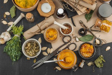 Kabak püresi, humus, bitkiler, kurutulmuş baharatlar, antika makas ve koyu ahşap arka planda antika nesnelerin yer aldığı taşralı natürmort hayat. Eczacı konsepti veya cadı ruhu, üst görünüm