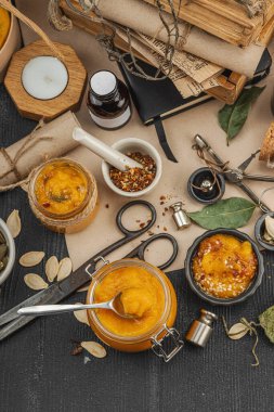 Kabak püresi, humus, bitkiler, kurutulmuş baharatlar, antika makas ve koyu ahşap arka planda antika nesnelerin yer aldığı taşralı natürmort hayat. Eczacı konsepti veya cadı ruhu, üst görünüm