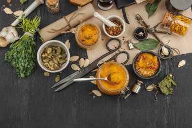 Kabak püresi, humus, bitkiler, kurutulmuş baharatlar, antika makas ve koyu ahşap arka planda antika nesnelerin yer aldığı taşralı natürmort hayat. Eczacı konsepti veya cadı ruhu, üst görünüm