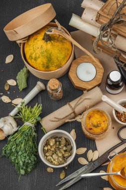 Kabak püresi, humus, bitkiler, kurutulmuş baharatlar, antika makas ve koyu ahşap arka planda antika nesnelerin yer aldığı taşralı natürmort hayat. Eczacı konsepti veya cadı ruhu, üst görünüm