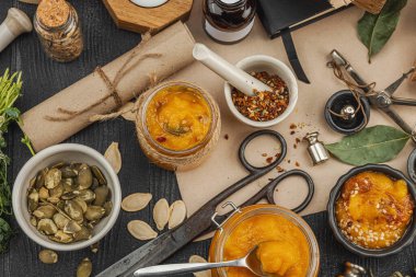 Kabak püresi, humus, bitkiler, kurutulmuş baharatlar, antika makas ve koyu ahşap arka planda antika nesnelerin yer aldığı taşralı natürmort hayat. Eczacı konsepti veya cadı ruhu, üst görünüm