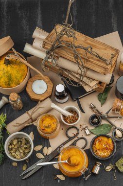 Kabak püresi, humus, bitkiler, kurutulmuş baharatlar, antika makas ve koyu ahşap arka planda antika nesnelerin yer aldığı taşralı natürmort hayat. Eczacı konsepti veya cadı ruhu, üst görünüm