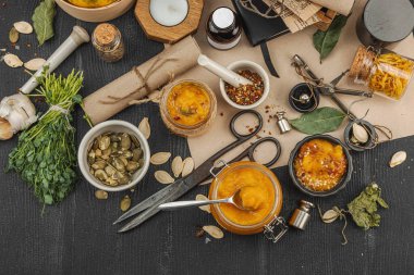 Kabak püresi, humus, bitkiler, kurutulmuş baharatlar, antika makas ve koyu ahşap arka planda antika nesnelerin yer aldığı taşralı natürmort hayat. Eczacı konsepti veya cadı ruhu, üst görünüm