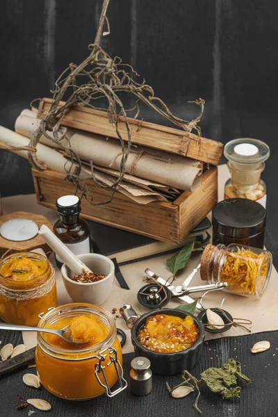 Kabak püresi, humus, bitkiler, kurutulmuş baharatlar, antika makas ve koyu ahşap arka planda antika nesnelerin yer aldığı taşralı natürmort hayat. Eczacı konsepti veya cadı ruhu, yaklaşın.