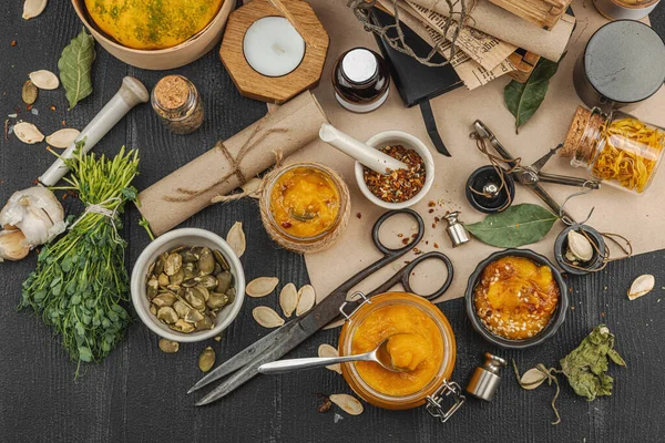 Kabak püresi, humus, bitkiler, kurutulmuş baharatlar, antika makas ve koyu ahşap arka planda antika nesnelerin yer aldığı taşralı natürmort hayat. Eczacı konsepti veya cadı ruhu, üst görünüm