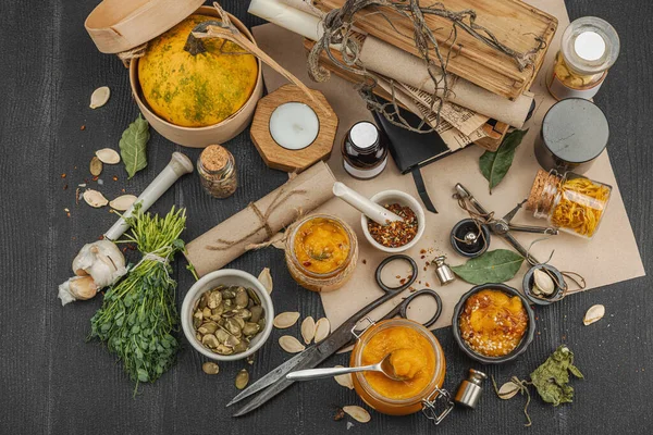 Kabak püresi, humus, bitkiler, kurutulmuş baharatlar, antika makas ve koyu ahşap arka planda antika nesnelerin yer aldığı taşralı natürmort hayat. Eczacı konsepti veya cadı ruhu, üst görünüm