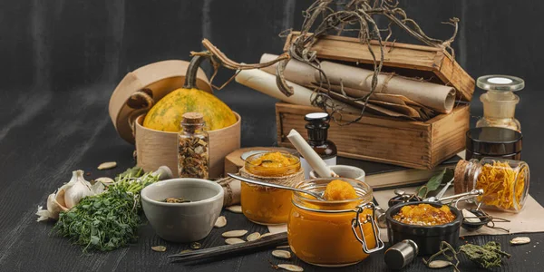 Kabak püresi, humus, bitkiler, kurutulmuş baharatlar, antika makas ve koyu ahşap arka planda antika nesnelerin yer aldığı taşralı natürmort hayat. Eczacı konsepti veya cadı ruhu, afiş biçimi