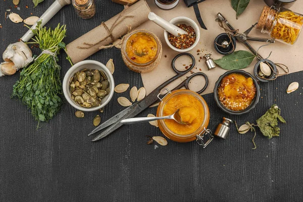 Kabak püresi, humus, bitkiler, kurutulmuş baharatlar, antika makas ve koyu ahşap arka planda antika nesnelerin yer aldığı taşralı natürmort hayat. Eczacı konsepti veya cadı ruhu, üst görünüm