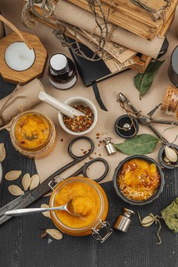 Kabak püresi, humus, bitkiler, kurutulmuş baharatlar, antika makas ve koyu ahşap arka planda antika nesnelerin yer aldığı taşralı natürmort hayat. Eczacı konsepti veya cadı ruhu, üst görünüm