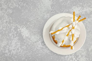 Beyaz şeker kaplı geleneksel Paskalya pastası ve beyaz tabakta dekoratif söğüt dalları. Minimalist şenlik, gri taş arka planda hayat, üst manzara