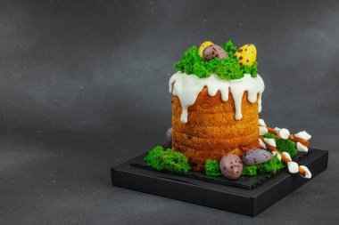 Yenilebilir yosun yuvası, çikolata yumurtası ve el yapımı söğüt dallarıyla süslenmiş Paskalya pastası. Siyah taş zemin üzerinde tavşan figürleri olan geleneksel şenlikli tatlı, kopyalama alanı