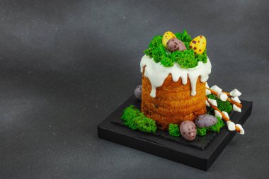 Yenilebilir yosun yuvası, çikolata yumurtası ve el yapımı söğüt dallarıyla süslenmiş Paskalya pastası. Siyah taş zemin üzerinde tavşan figürleri olan geleneksel şenlikli tatlı, kopyalama alanı