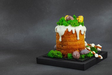 Yenilebilir yosun yuvası, çikolata yumurtası ve el yapımı söğüt dallarıyla süslenmiş Paskalya pastası. Siyah taş zemin üzerinde tavşan figürleri olan geleneksel şenlikli tatlı, kopyalama alanı