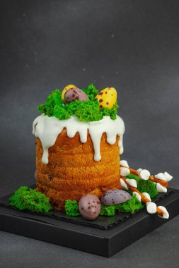 Yenilebilir yosun yuvası, çikolata yumurtası ve el yapımı söğüt dallarıyla süslenmiş Paskalya pastası. Siyah taş zemin üzerinde tavşan figürleri olan geleneksel şenlikli tatlı, kopyalama alanı