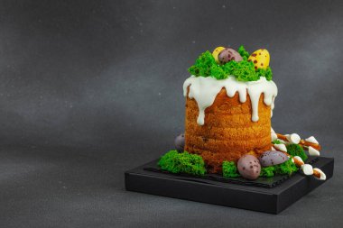 Yenilebilir yosun yuvası, çikolata yumurtası ve el yapımı söğüt dallarıyla süslenmiş Paskalya pastası. Siyah taş zemin üzerinde tavşan figürleri olan geleneksel şenlikli tatlı, kopyalama alanı