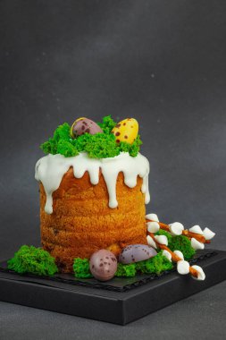 Yenilebilir yosun yuvası, çikolata yumurtası ve el yapımı söğüt dallarıyla süslenmiş Paskalya pastası. Siyah taş zemin üzerinde tavşan figürleri olan geleneksel şenlikli tatlı, kopyalama alanı