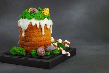 Yenilebilir yosun yuvası, çikolata yumurtası ve el yapımı söğüt dallarıyla süslenmiş Paskalya pastası. Siyah taş zemin üzerinde tavşan figürleri olan geleneksel şenlikli tatlı, kopyalama alanı