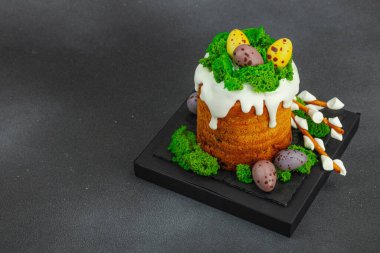 Yenilebilir yosun yuvası, çikolata yumurtası ve el yapımı söğüt dallarıyla süslenmiş Paskalya pastası. Siyah taş zemin üzerinde tavşan figürleri olan geleneksel şenlikli tatlı, kopyalama alanı