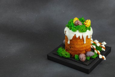 Yenilebilir yosun yuvası, çikolata yumurtası ve el yapımı söğüt dallarıyla süslenmiş Paskalya pastası. Siyah taş zemin üzerinde tavşan figürleri olan geleneksel şenlikli tatlı, kopyalama alanı