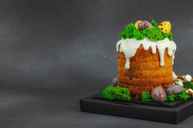 Yenilebilir yosun yuvası, çikolata yumurtası ve el yapımı söğüt dallarıyla süslenmiş Paskalya pastası. Siyah taş zemin üzerinde tavşan figürleri olan geleneksel şenlikli tatlı, kopyalama alanı