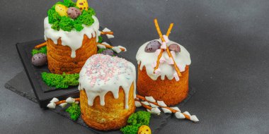 Yenilebilir yosun yuvası, çikolata yumurtası ve el yapımı söğüt dallarıyla süslenmiş paskalya pastaları. Siyah taş zemin üzerinde tavşan figürleri olan geleneksel şenlikli tatlı, afiş biçimi