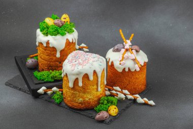 Yenilebilir yosun yuvası, çikolata yumurtası ve el yapımı söğüt dallarıyla süslenmiş paskalya pastaları. Siyah taş zemin üzerinde tavşan figürleri olan geleneksel şenlikli tatlı, kopyalama alanı