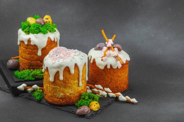 Yenilebilir yosun yuvası, çikolata yumurtası ve el yapımı söğüt dallarıyla süslenmiş paskalya pastaları. Siyah taş zemin üzerinde tavşan figürleri olan geleneksel şenlikli tatlı, kopyalama alanı