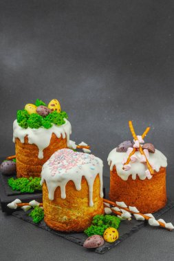 Yenilebilir yosun yuvası, çikolata yumurtası ve el yapımı söğüt dallarıyla süslenmiş paskalya pastaları. Siyah taş zemin üzerinde tavşan figürleri olan geleneksel şenlikli tatlı, kopyalama alanı