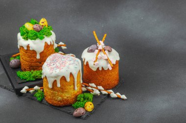Yenilebilir yosun yuvası, çikolata yumurtası ve el yapımı söğüt dallarıyla süslenmiş paskalya pastaları. Siyah taş zemin üzerinde tavşan figürleri olan geleneksel şenlikli tatlı, kopyalama alanı
