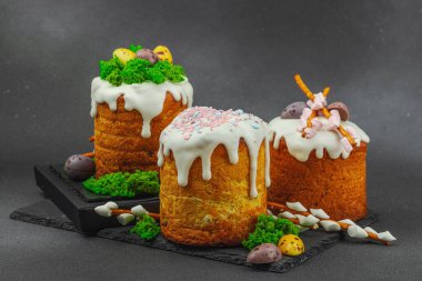 Yenilebilir yosun yuvası, çikolata yumurtası ve el yapımı söğüt dallarıyla süslenmiş paskalya pastaları. Siyah taş zemin üzerinde tavşan figürleri olan geleneksel şenlikli tatlı, kopyalama alanı