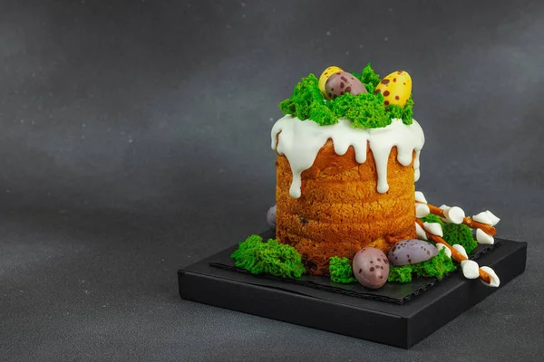 Yenilebilir yosun yuvası, çikolata yumurtası ve el yapımı söğüt dallarıyla süslenmiş Paskalya pastası. Siyah taş zemin üzerinde tavşan figürleri olan geleneksel şenlikli tatlı, kopyalama alanı