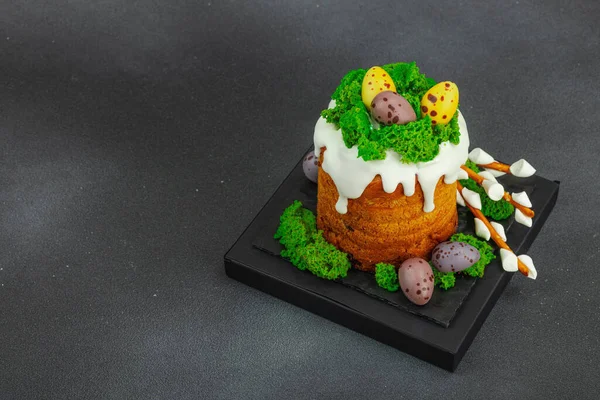 Yenilebilir yosun yuvası, çikolata yumurtası ve el yapımı söğüt dallarıyla süslenmiş Paskalya pastası. Siyah taş zemin üzerinde tavşan figürleri olan geleneksel şenlikli tatlı, kopyalama alanı