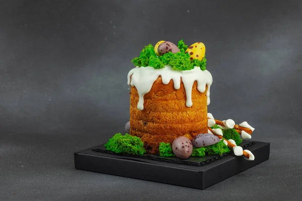 Yenilebilir yosun yuvası, çikolata yumurtası ve el yapımı söğüt dallarıyla süslenmiş Paskalya pastası. Siyah taş zemin üzerinde tavşan figürleri olan geleneksel şenlikli tatlı, kopyalama alanı