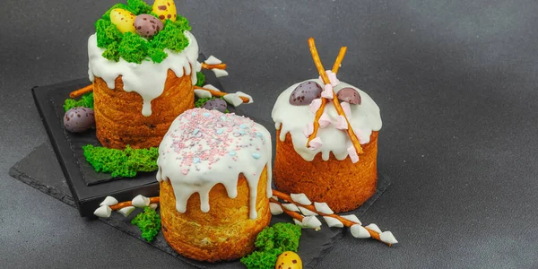 Yenilebilir yosun yuvası, çikolata yumurtası ve el yapımı söğüt dallarıyla süslenmiş paskalya pastaları. Siyah taş zemin üzerinde tavşan figürleri olan geleneksel şenlikli tatlı, afiş biçimi