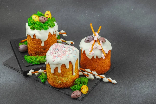 Yenilebilir yosun yuvası, çikolata yumurtası ve el yapımı söğüt dallarıyla süslenmiş paskalya pastaları. Siyah taş zemin üzerinde tavşan figürleri olan geleneksel şenlikli tatlı, kopyalama alanı