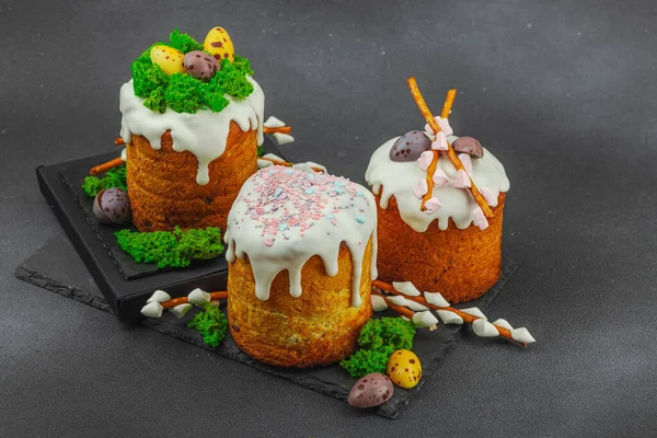 Yenilebilir yosun yuvası, çikolata yumurtası ve el yapımı söğüt dallarıyla süslenmiş paskalya pastaları. Siyah taş zemin üzerinde tavşan figürleri olan geleneksel şenlikli tatlı, kopyalama alanı