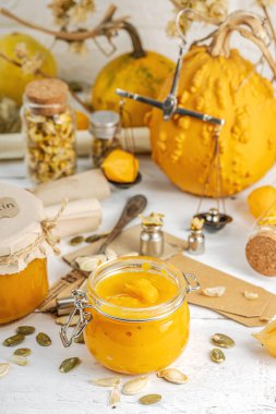 Antika eczacılık tarzında sağlıklı gıda konsepti. Ev yapımı kabak püresi ve beyaz ahşap bir masada cam kavanozlarda humus. Kabak, kurutulmuş zıpzıp ve bitki örtüsüyle dolu kırsal bir sonbahar hayatı. Kapan.