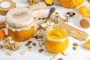 Antika eczacılık tarzında sağlıklı gıda konsepti. Ev yapımı kabak püresi ve beyaz ahşap bir masada cam kavanozlarda humus. Kabak, kurutulmuş zıpzıp ve bitki örtüsüyle dolu kırsal bir sonbahar hayatı. Kapan.