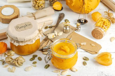 Antika eczacılık tarzında sağlıklı gıda konsepti. Ev yapımı kabak püresi ve beyaz ahşap bir masada cam kavanozlarda humus. Kabak, kurutulmuş zıpzıp ve bitki örtüsüyle dolu kırsal bir sonbahar hayatı. Kapan.