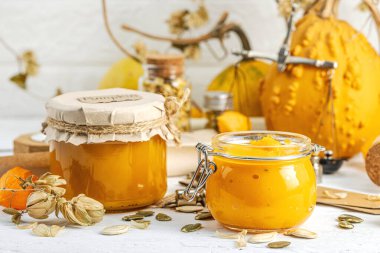 Antika eczacılık tarzında sağlıklı gıda konsepti. Ev yapımı kabak püresi ve beyaz ahşap bir masada cam kavanozlarda humus. Kabak, kurutulmuş zıpzıp ve bitki örtüsüyle dolu kırsal bir sonbahar hayatı. Kapan.