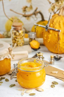 Antika eczacılık tarzında sağlıklı gıda konsepti. Ev yapımı kabak püresi ve beyaz ahşap bir masada cam kavanozlarda humus. Kabak, kurutulmuş zıpzıp ve bitki örtüsüyle dolu kırsal bir sonbahar hayatı. Kapan.