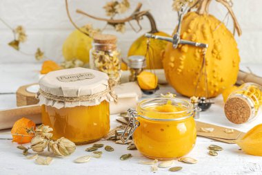 Antika eczacılık tarzında sağlıklı gıda konsepti. Ev yapımı kabak püresi ve beyaz ahşap bir masada cam kavanozlarda humus. Kabak, kurutulmuş zıpzıp ve bitki örtüsüyle dolu kırsal bir sonbahar hayatı. Kapan.