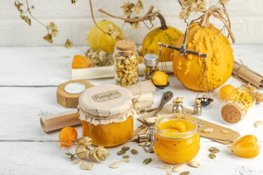 Antika eczacılık tarzında sağlıklı gıda konsepti. Ev yapımı kabak püresi ve beyaz ahşap bir masada cam kavanozlarda humus. Balkabağı, kurutulmuş zıpzıp ve bitki özü ile kırsal sonbahar natürmortu, kopyalama alanı
